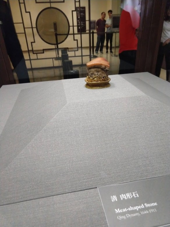 A picture of a carving in a display case that looks like a piece of pork belly.