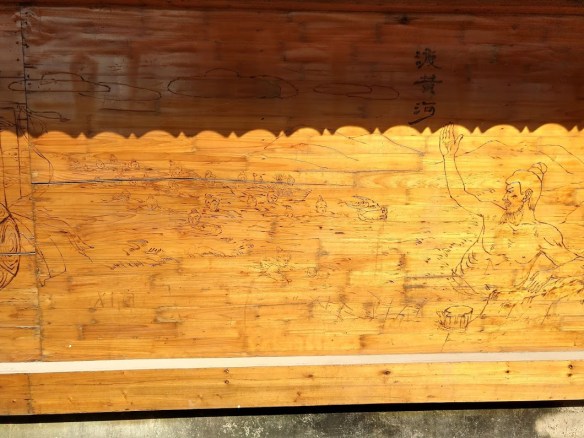 A carved wood panel depicting a man swimming across a river and encouraging others to follow him.