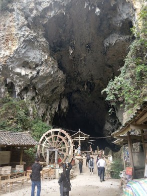 A natural cave rising up over a water wheel.