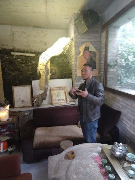 An artist standing next to a lamp made from handmade paper, which looks sort of like a glowing wasp's nest.
