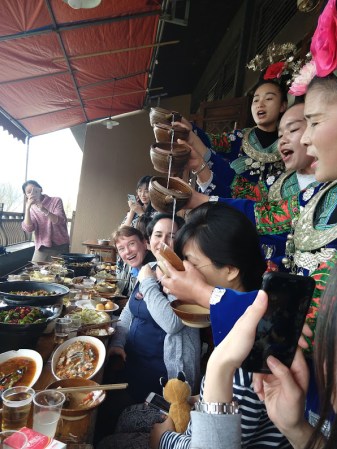 Tang Fei drinking rice wine that's being poured out of a pitcher, that's being refilled by a higher pitcher, creating a sort of choreographed fountain of booze.