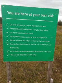 A sign saying "You are here at your own risk" and listing a number of rules for safely being near a hot spring, including a final note, "The nearest hospital is 62 km away."