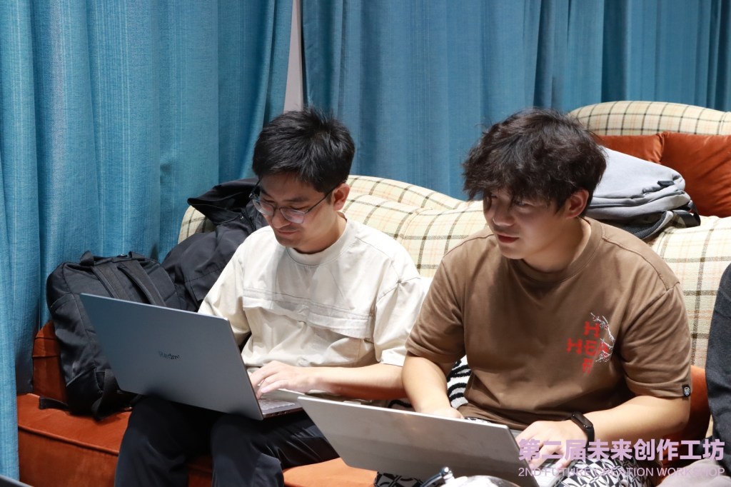 Two men sitting on a couch, both with laptops out.